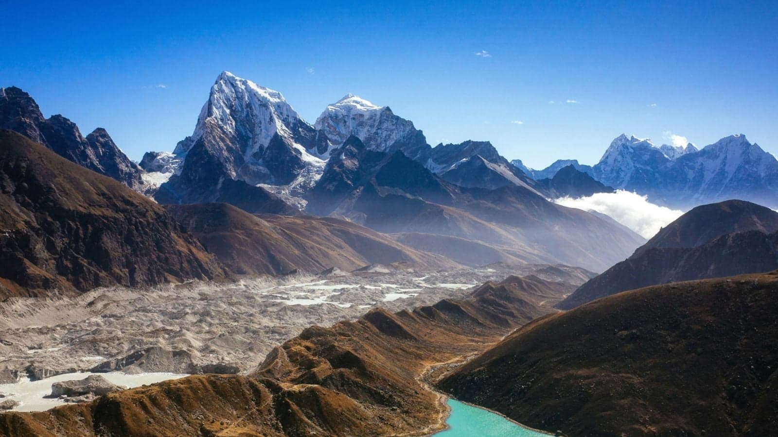 Gokyo village and turquoise Gokyo Lake beside the Ngozumpa Glacier, with snow peaks of the Everest region behind