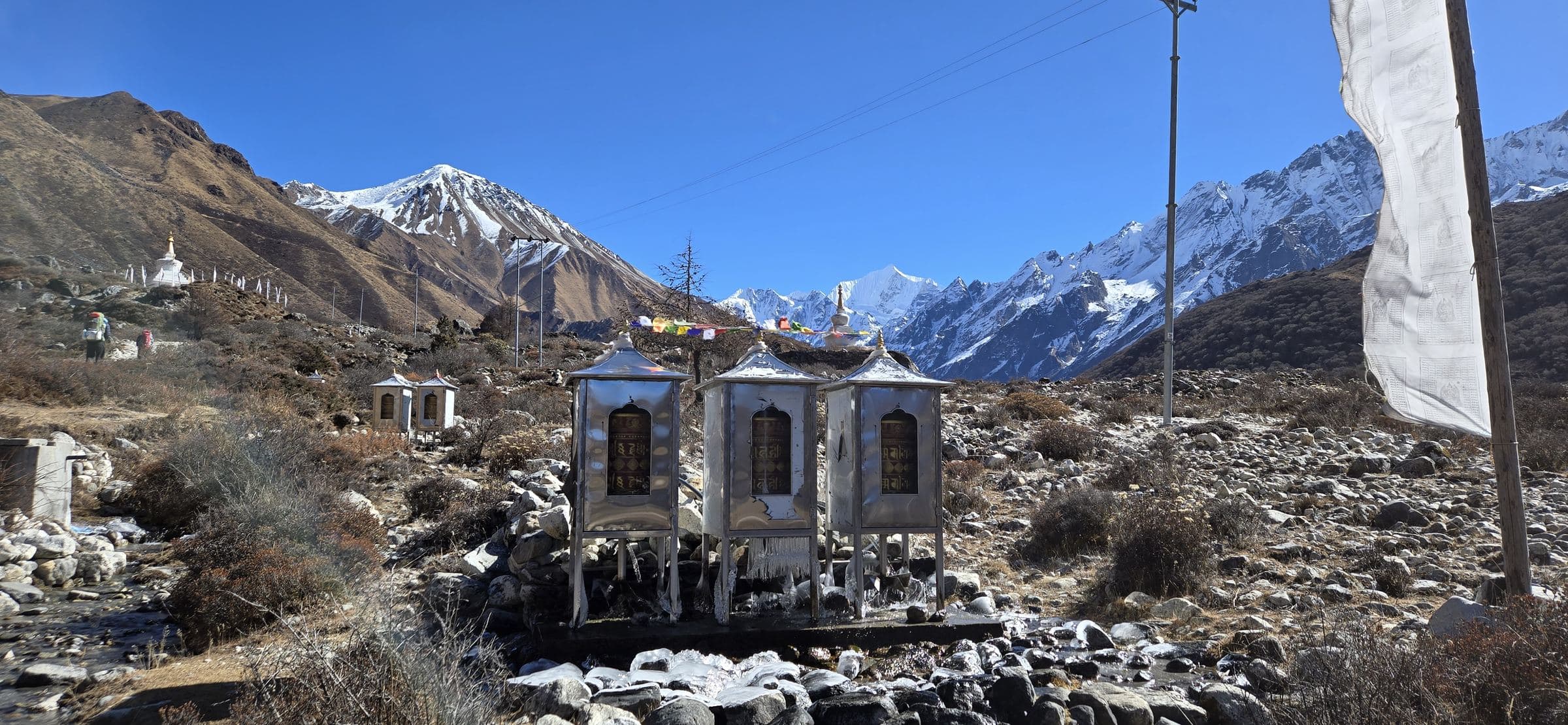 Prayer wheels at Kyanjin Gompa with the snow peaks of the Langtang valley behind
